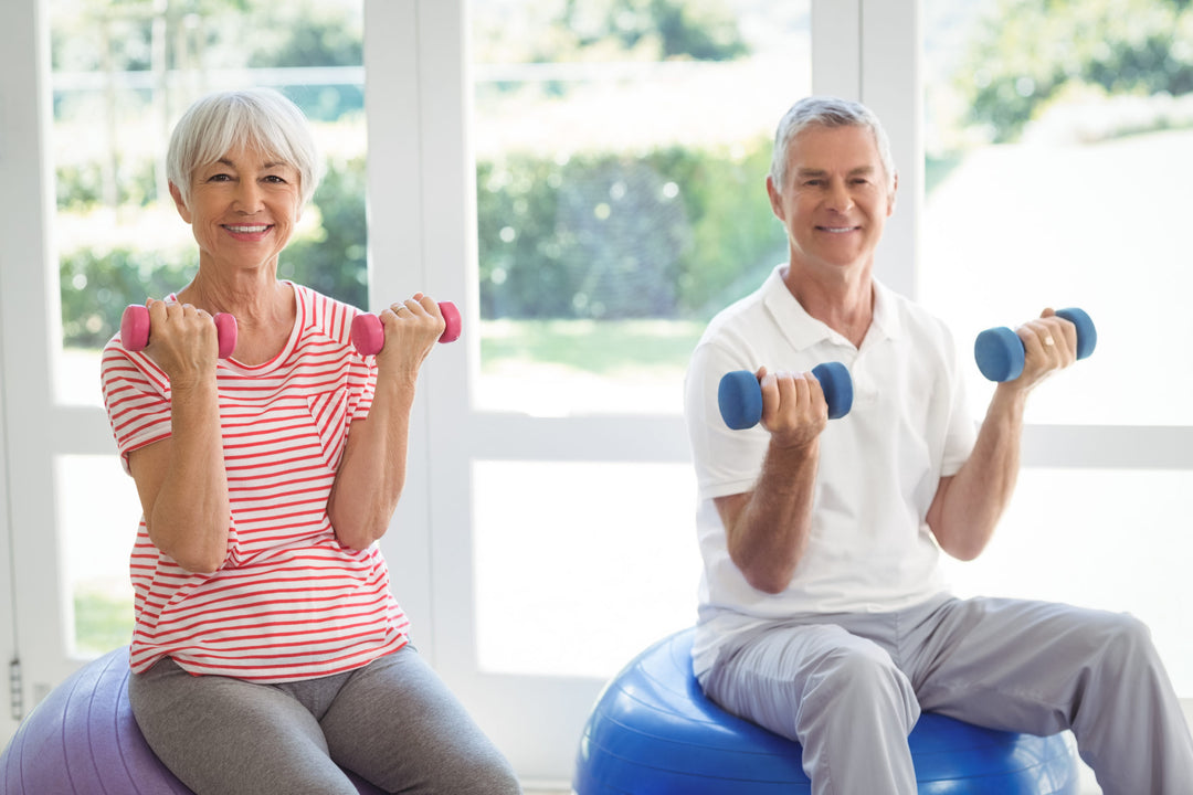 Senior couple exercising with dumbbells on exercise ball at home